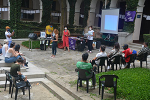 Foto de pessoas sentadas em cadeiras que assistem a uma apresentação no Pátio da Cruz, no Campus Monte Alegre