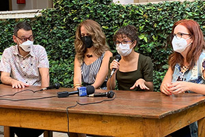 Foto com destaque de quatro pessoas participantes de uma mesa de palestra, sendo uma delas ao microfone, no Campus Monte Alegre